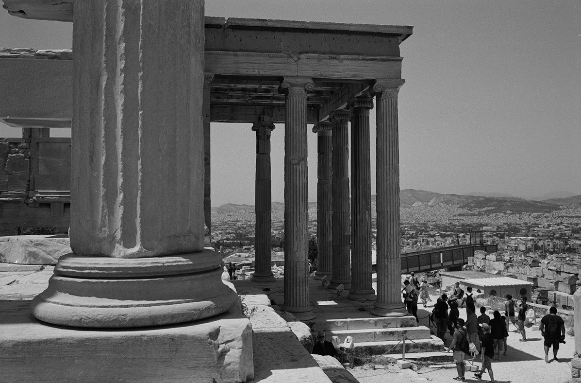 Photographie de rue montrant un matelas et quelques affaires appartenant à un SDF à Lyon, avec en perspective 2 hommes de dos discutant