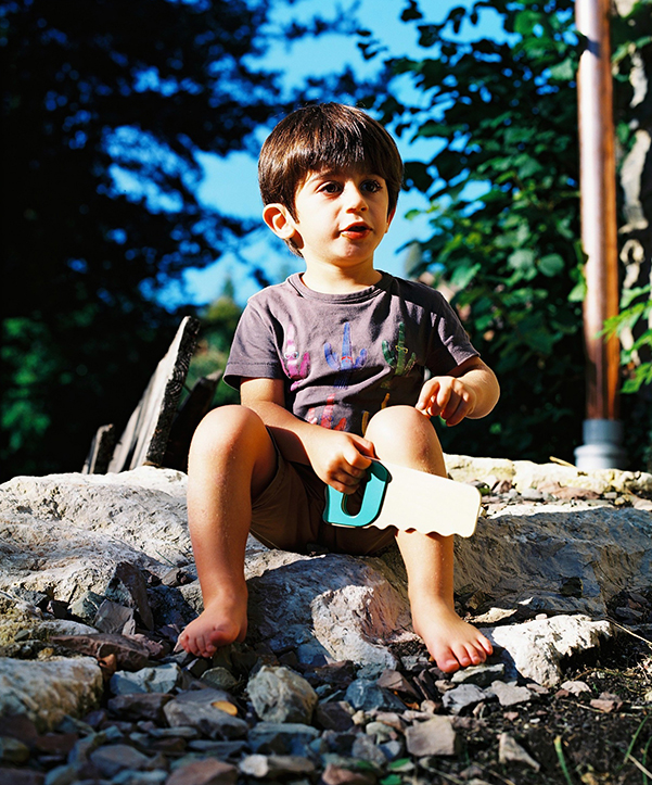 Portrait du fils d'un ami jouant avec une scie en bois