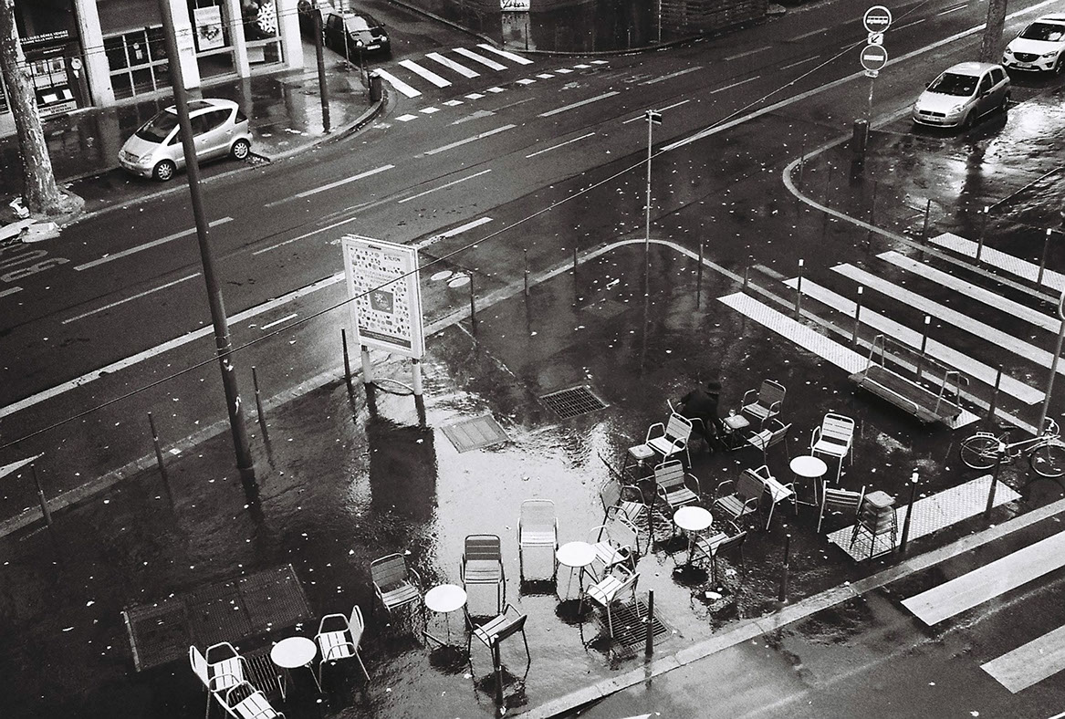 Photographie de rue montrant un matelas et quelques affaires appartenant à un SDF à Lyon, avec en perspective 2 hommes de dos discutant