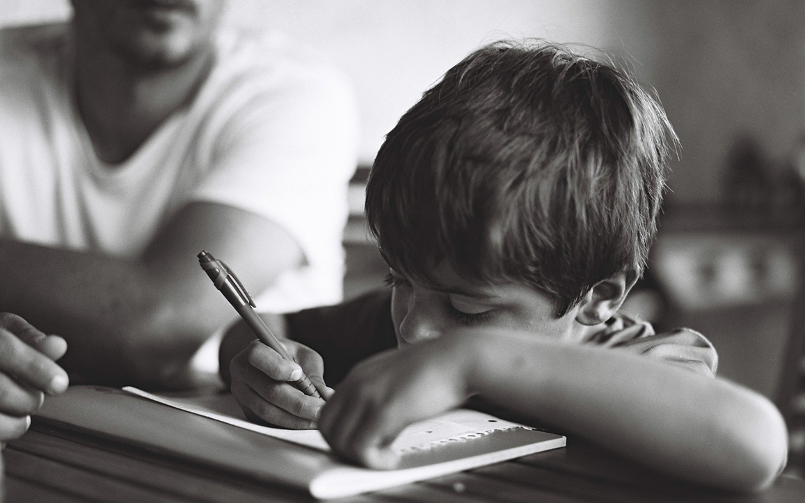 Portrait d'un enfant faisant ses devoirs aux côtés de son père